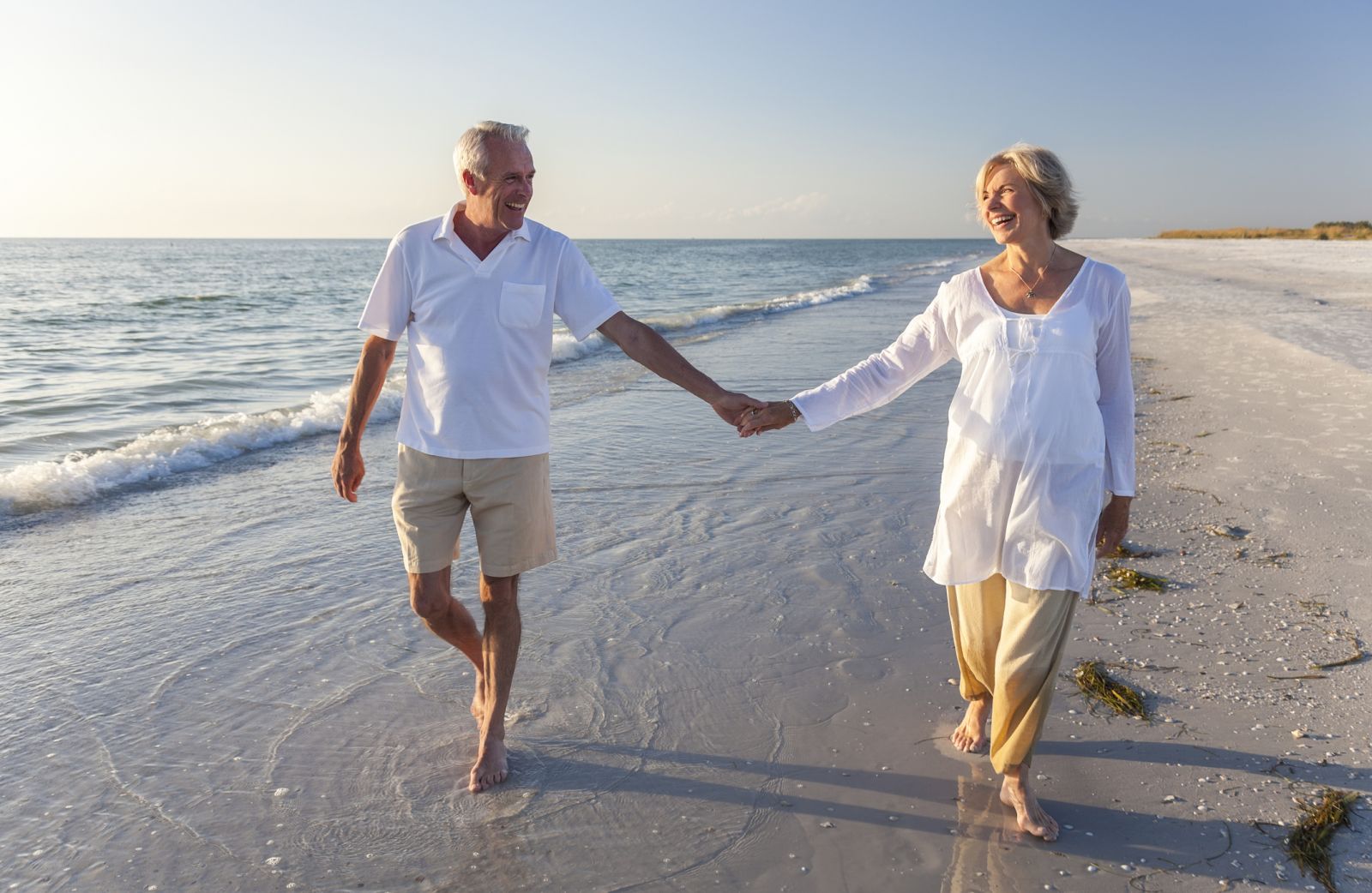 senior couple holding hands on beach